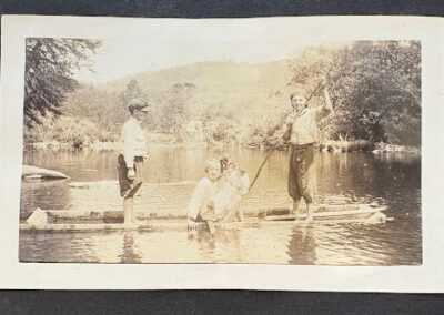 Three children sitting in a small wooden boat on the water
