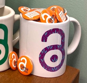 Mug with Open Access logo filled with Open Access pins