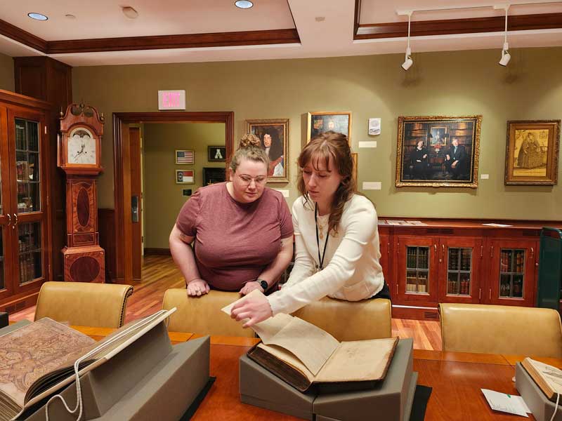 Hannah Helmey shows a rare boook to a visitor in the Rhinehart Room 