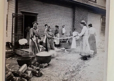 Women gathered outside with wash pots and firewood, possibly preparing laundry