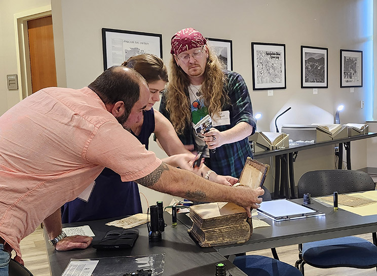 multispectral_study_ Participants examine a manuscript book with multispectural imaging
