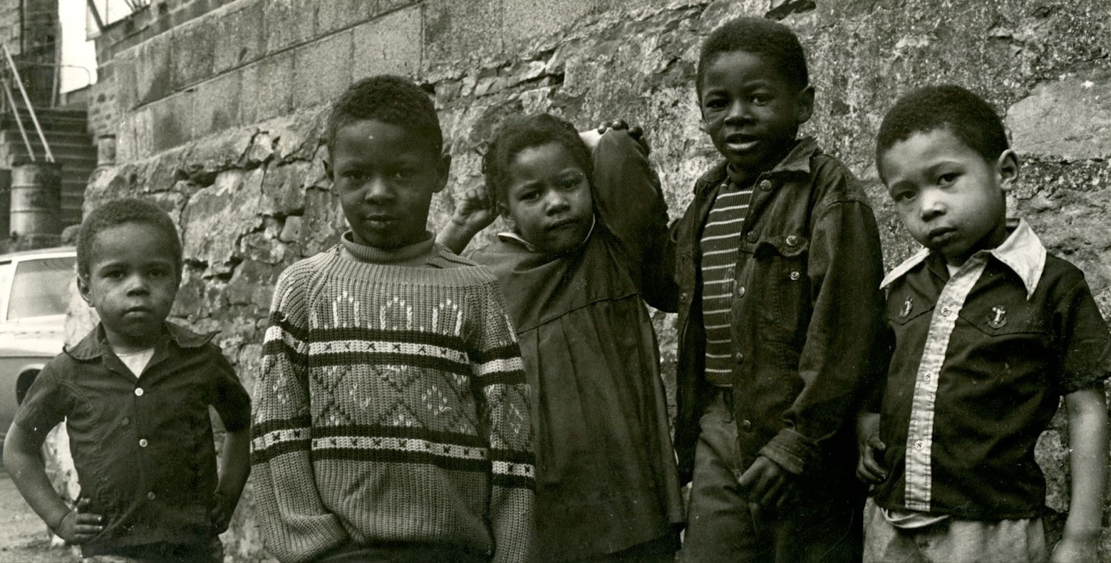 Black and white photo of five young children standing outside a building
