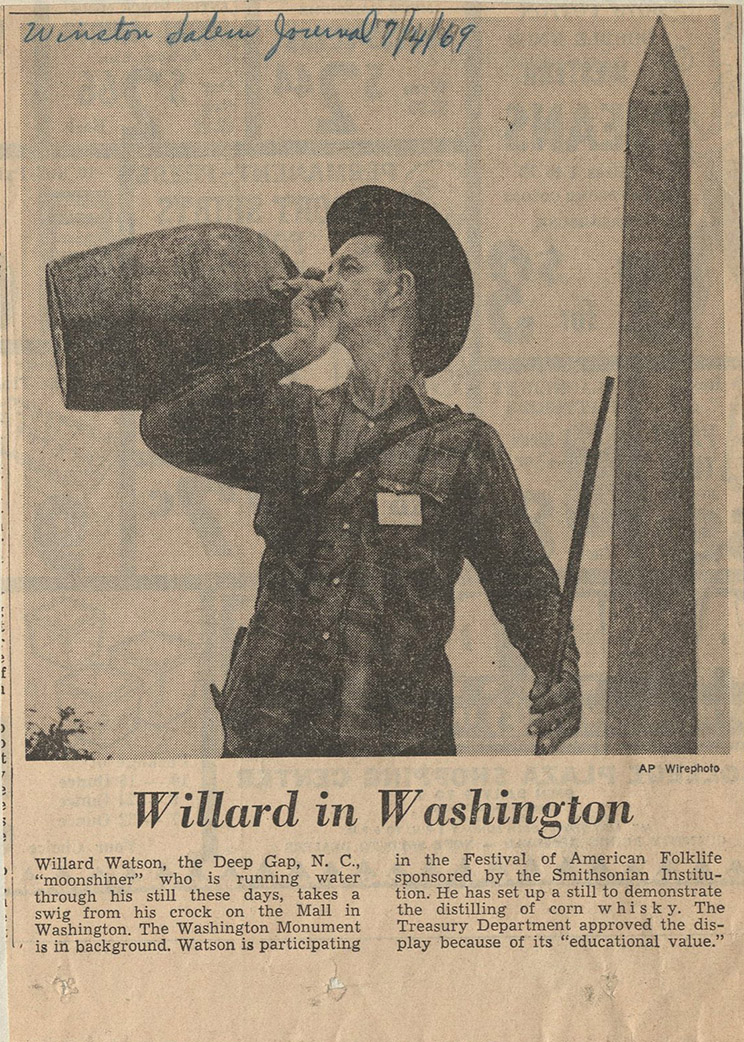 Clipping from the July 4, 1969 Winston Salem Journal newspaper showing Watson with a jug of moonshine in front of the Washington monument. The text describes Watson's trip to the Smithsonian's folklife festival to demonstrate corn whiskey distilling.