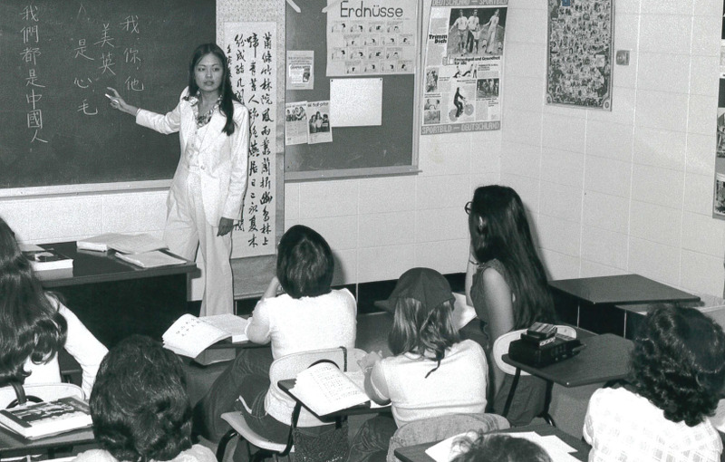 Black and white photo of professor at chalkboard and students seated at desk